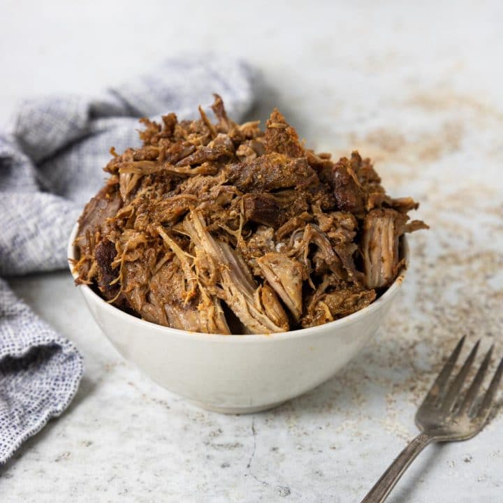 whole30 pulled pork in a bowl with a fork and napkin to the side