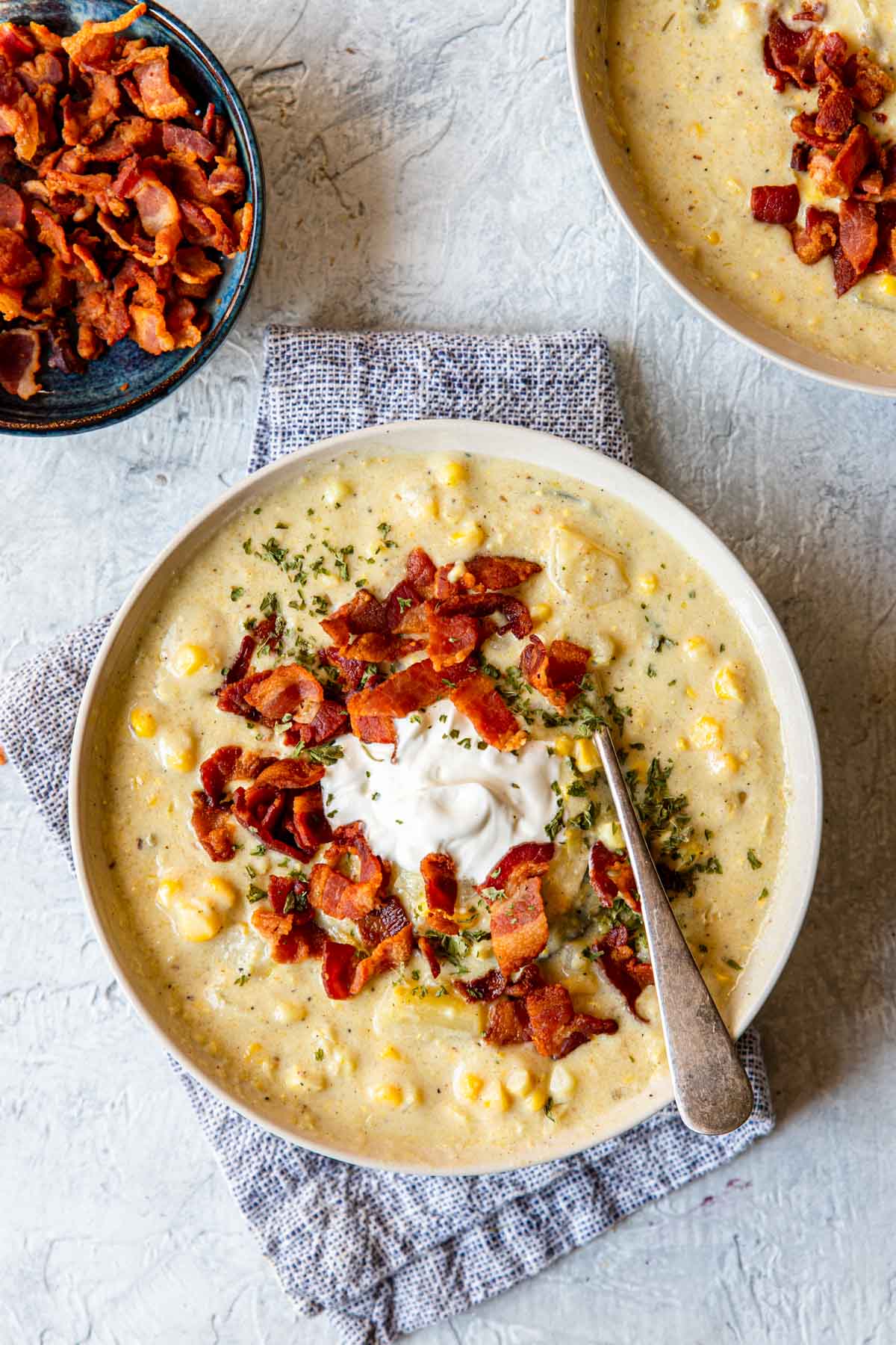 corn chowder in a bowl topped with sour cream and bacon