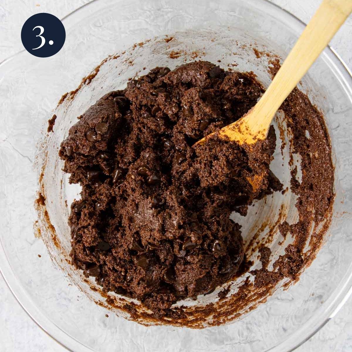 brownie batter in a bowl with a wooden spoon