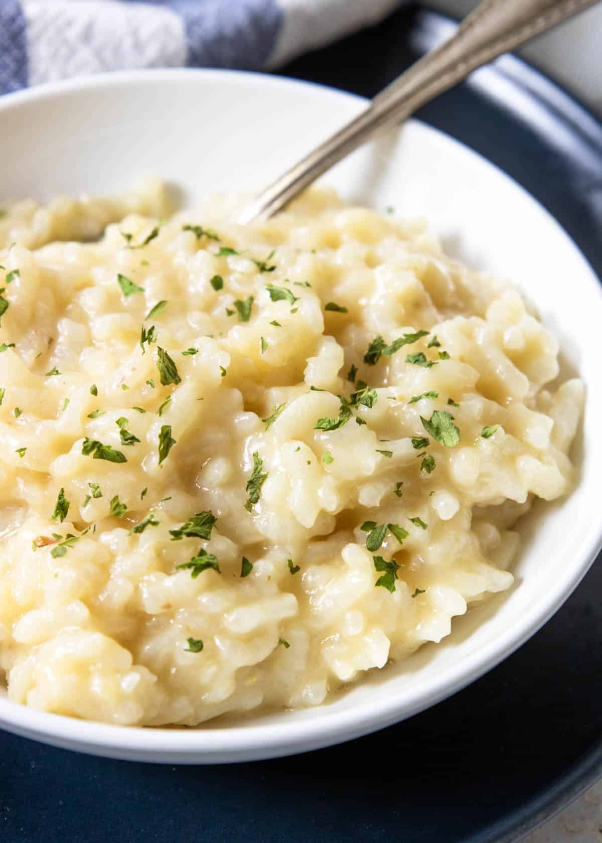 creamy risotto in a white bowl with a spoon