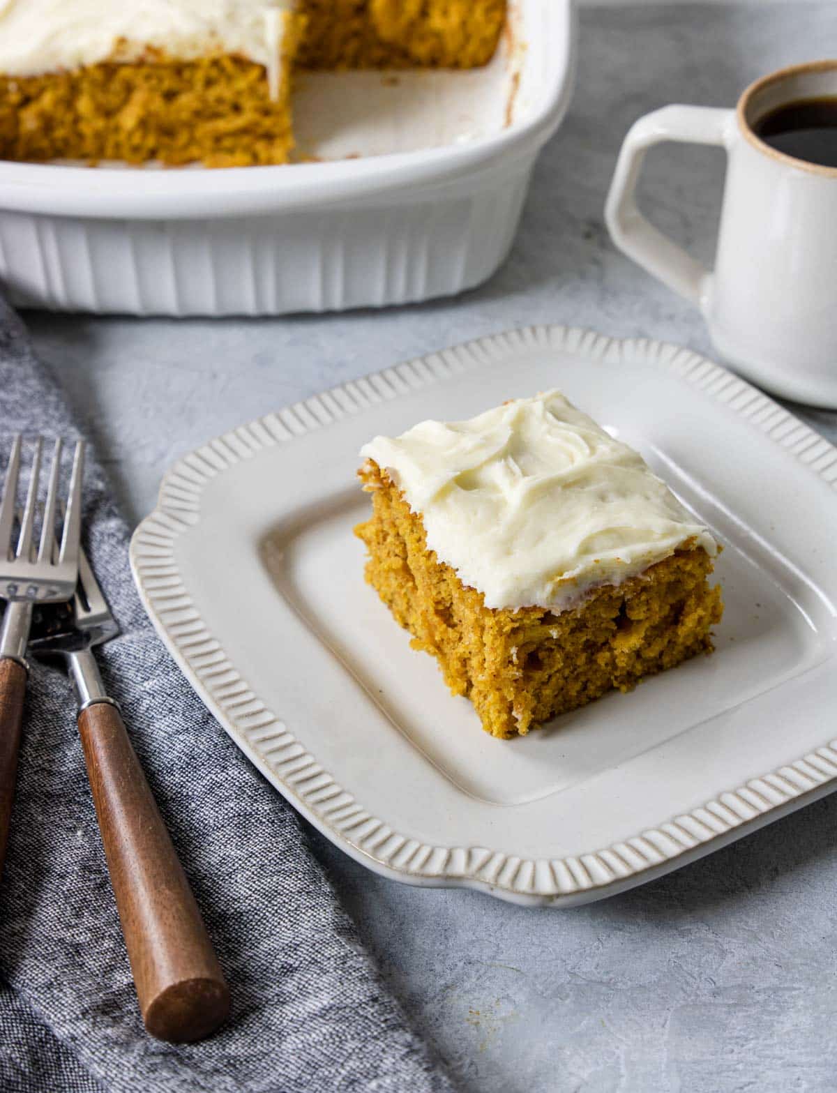pumpkin bar with icing on a  plate with a cup of coffee