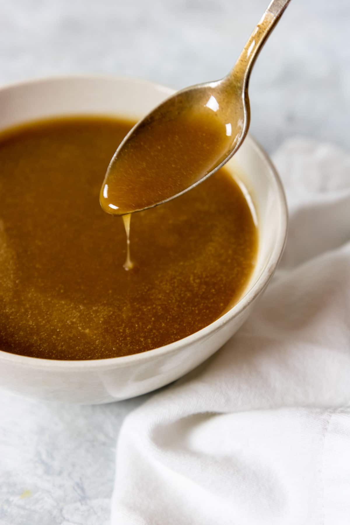 brown sugar caramel sauce on a spoon drizzling into a bowl