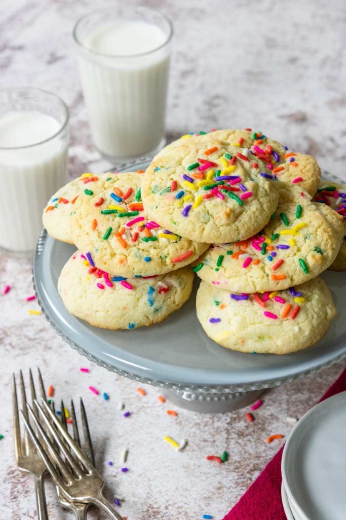 funfetti cookies on a cake plate with milk in the background