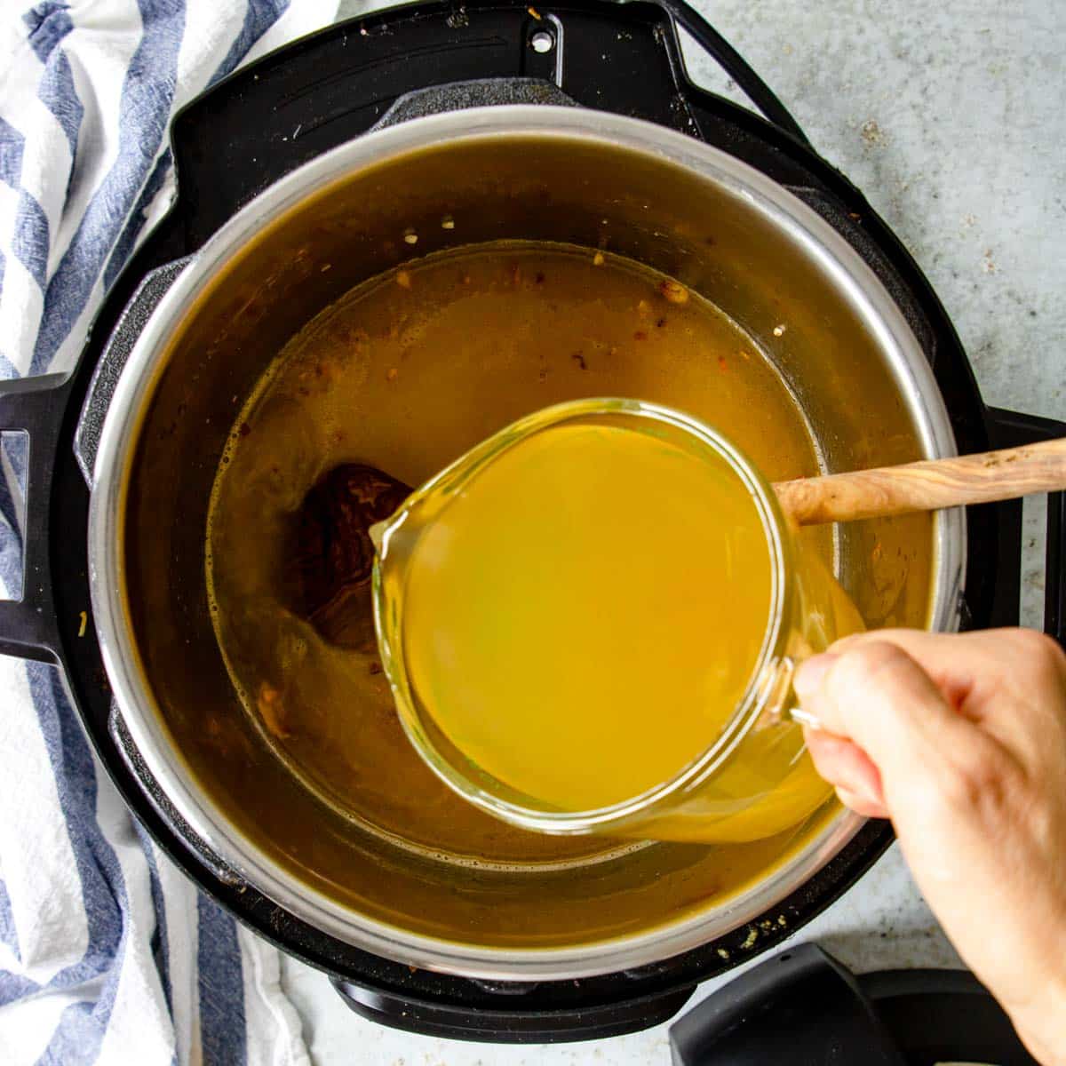 Pouring chicken broth and wine into the Instant Pot 