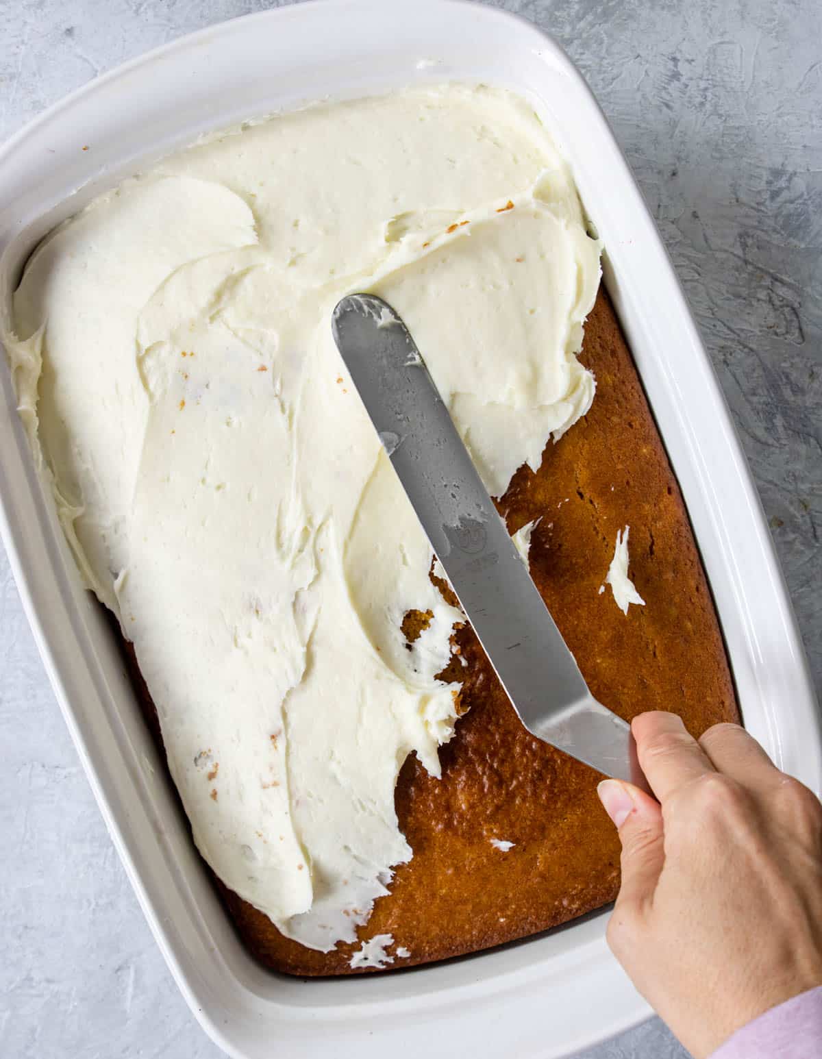 frosting pumpkin bars with an offset spatula