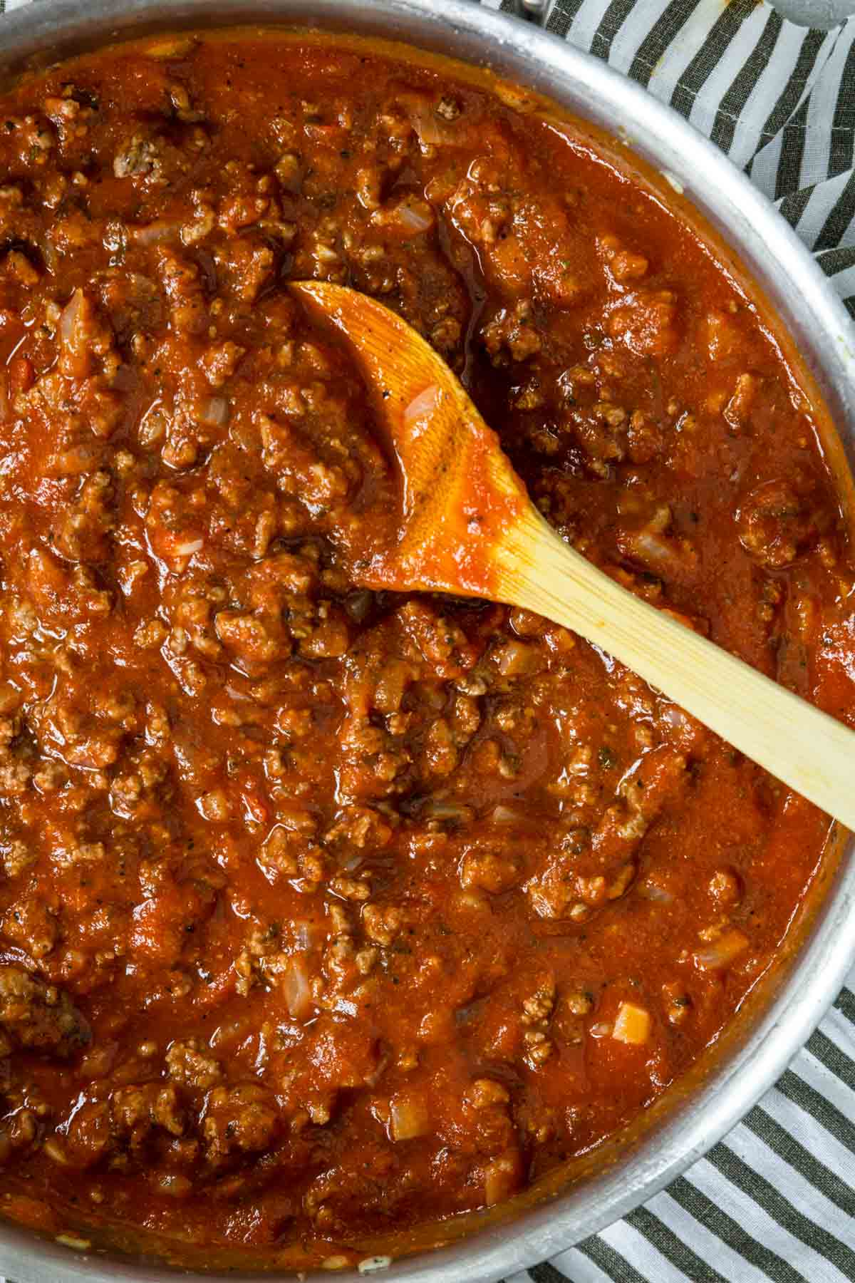 meat sauce in a skillet with a wooden spoon