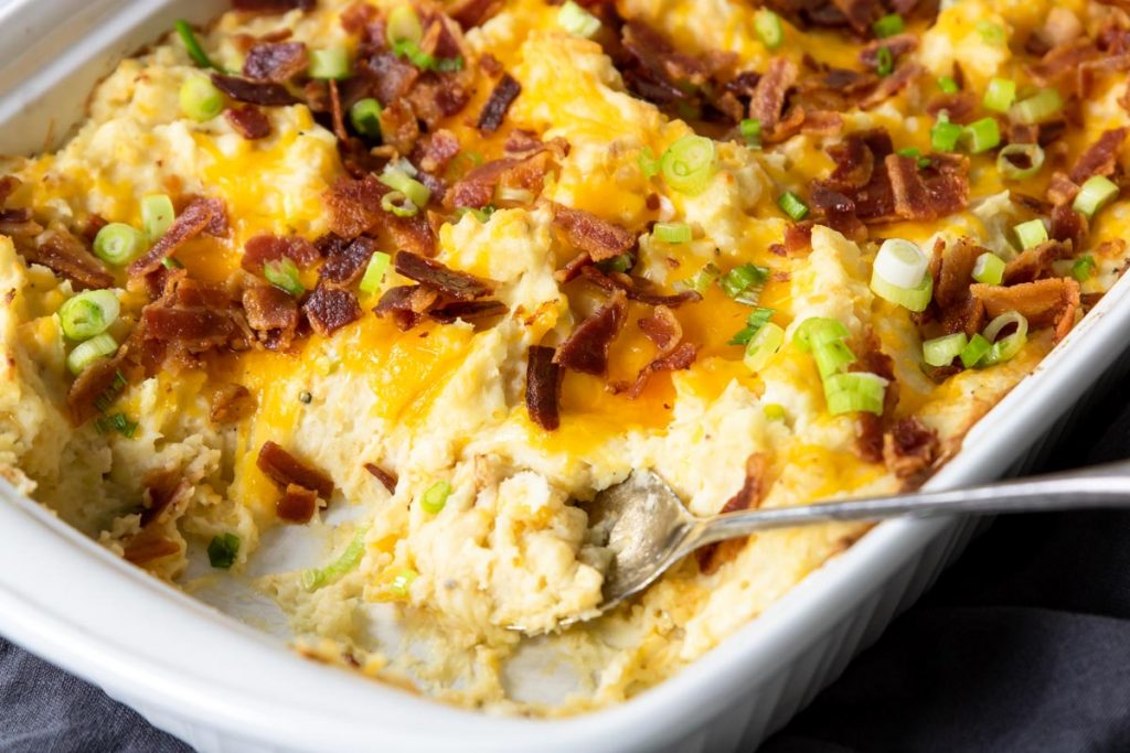 mashed potato casserole topped with cheese, green onions and bacon