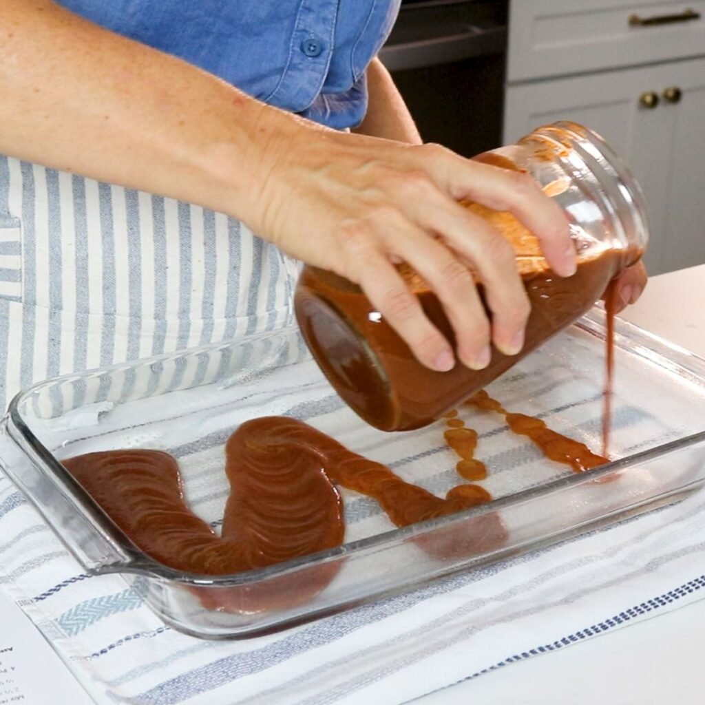 Pouring red enchilada sauce into a 9x13 pan