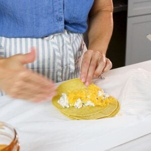rolling a cream cheese chicken enchilada with a little cheese on top