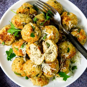 baked chicken meatballs in a pile garnished with parsley and romano cheese