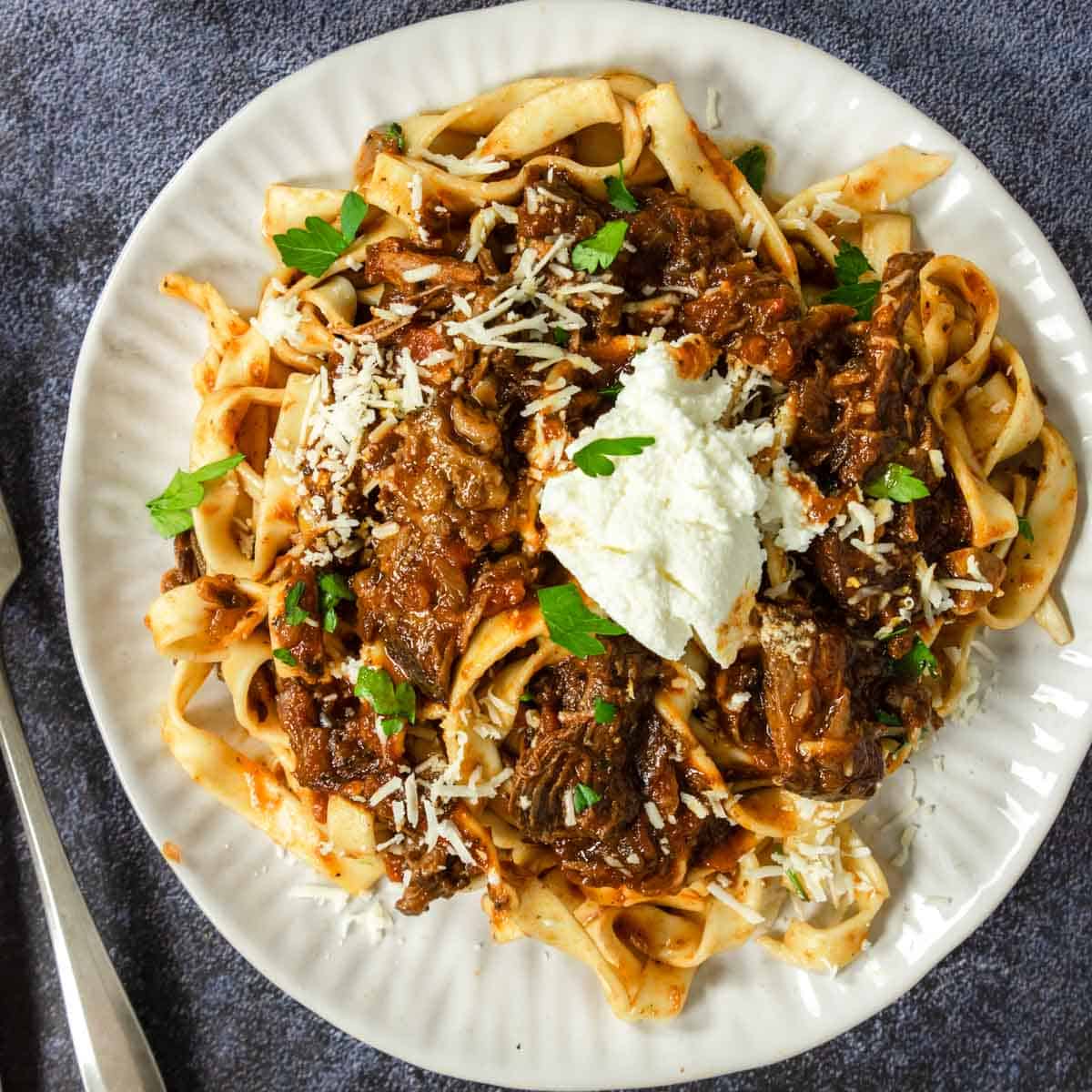 Papardelle pasta topped with beef ragu and a dallop of ricotta cheese