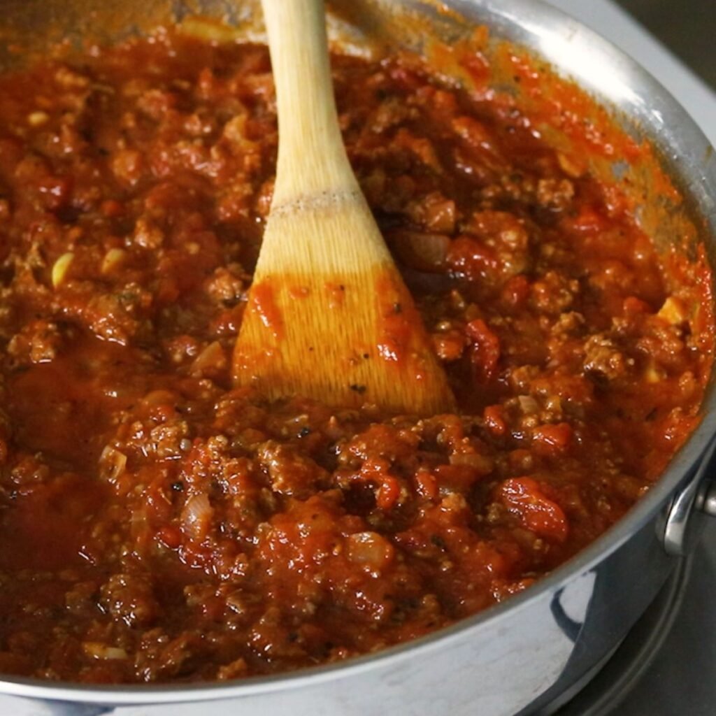 Adding sauce to browned ground beef with onions and garlic