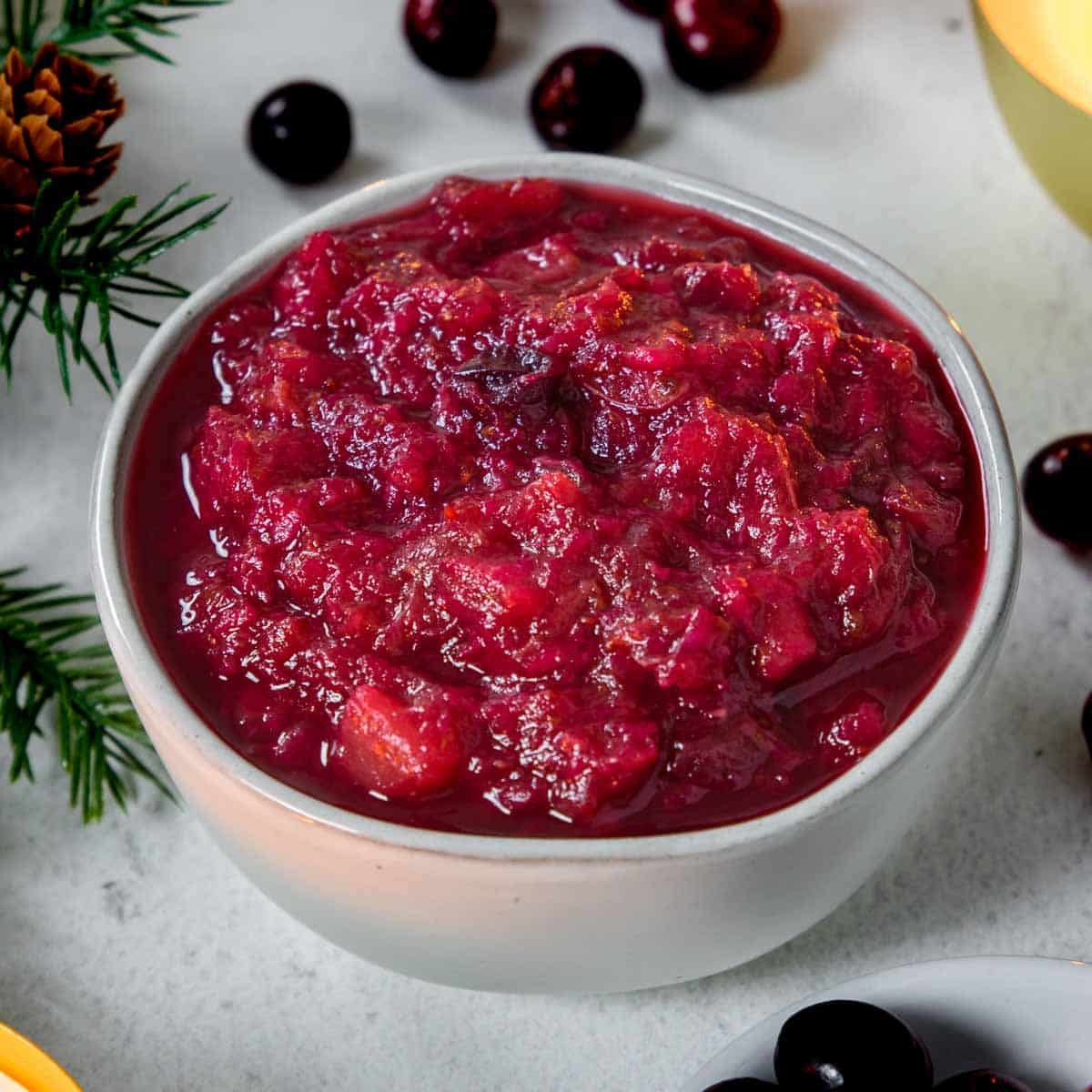 Instant Pot Cranberries in a bowl with fresh cranberries around the side of the bowl