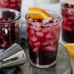 pomegranate margarita in a tall glass with orange and arils