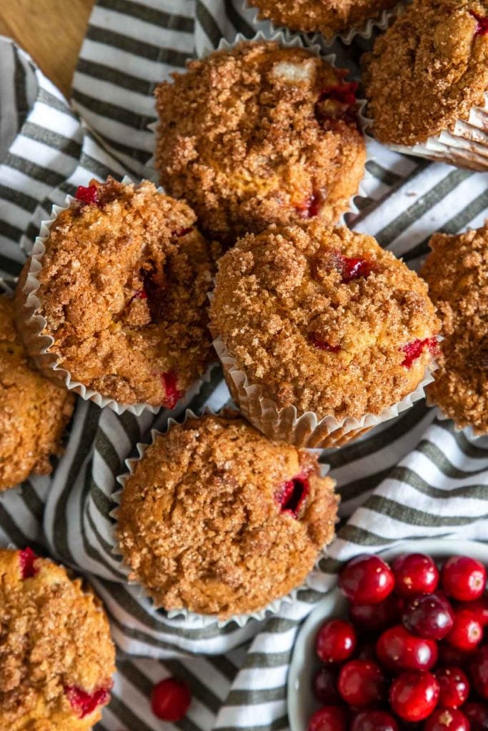 Cranberry orange muffins on a black and white napkin with fresh cranberries