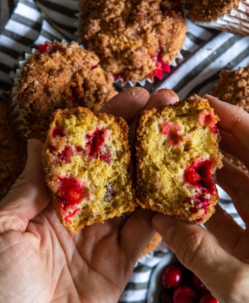 cranberry muffin broken open to show the inside with is orange with bright red cranberries