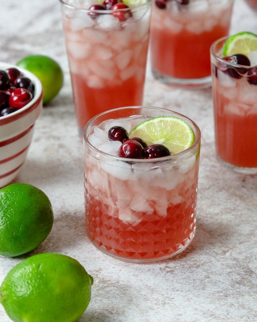 cranberry punch in a glass over ice garnished with cranberries and limes