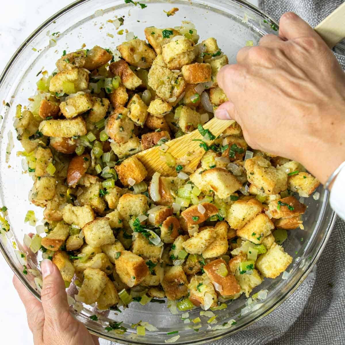 Stirring homemade stuffing together in a large bowl