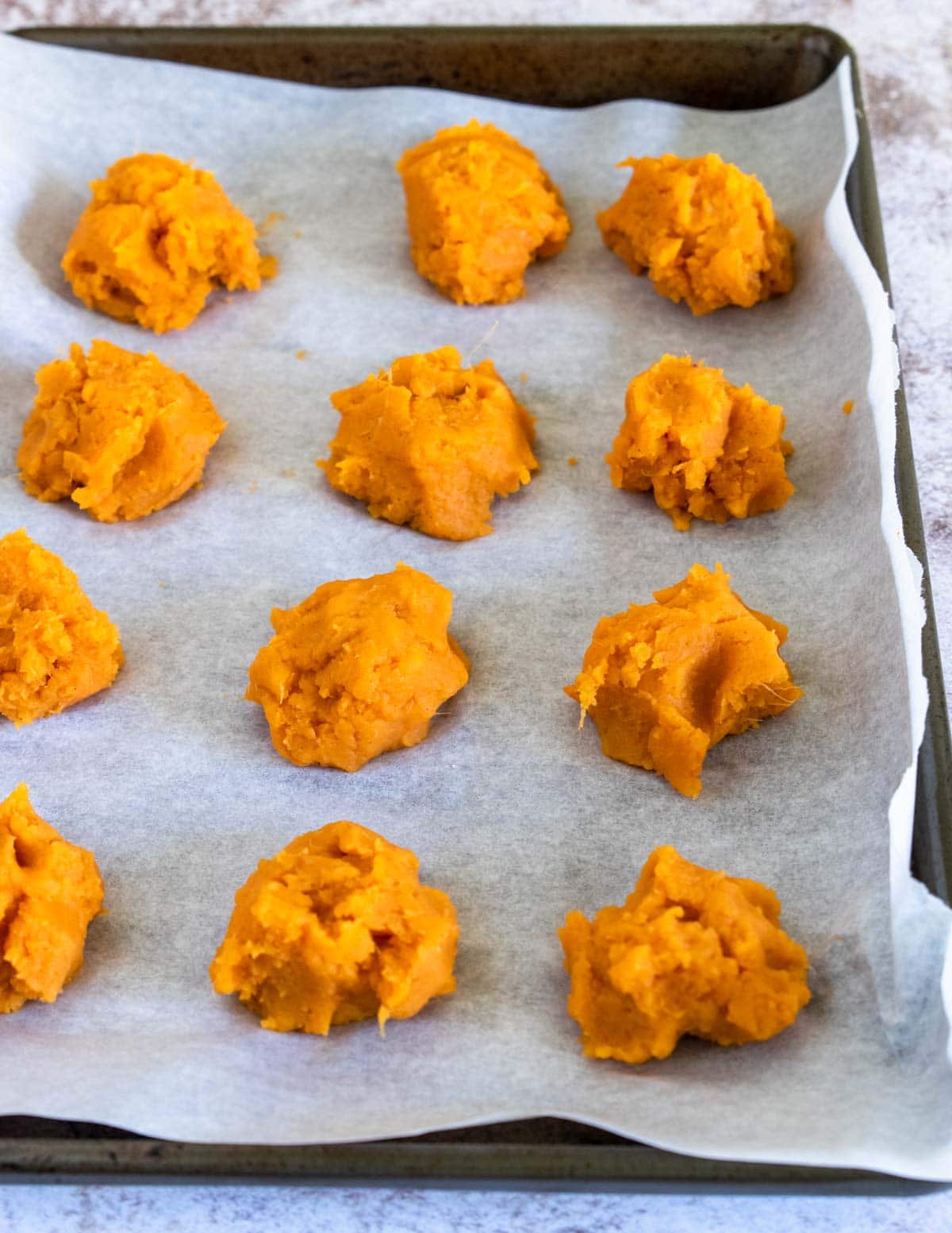 pucks of mashed sweet potatoes on a baking sheet with parchment, for the freezer