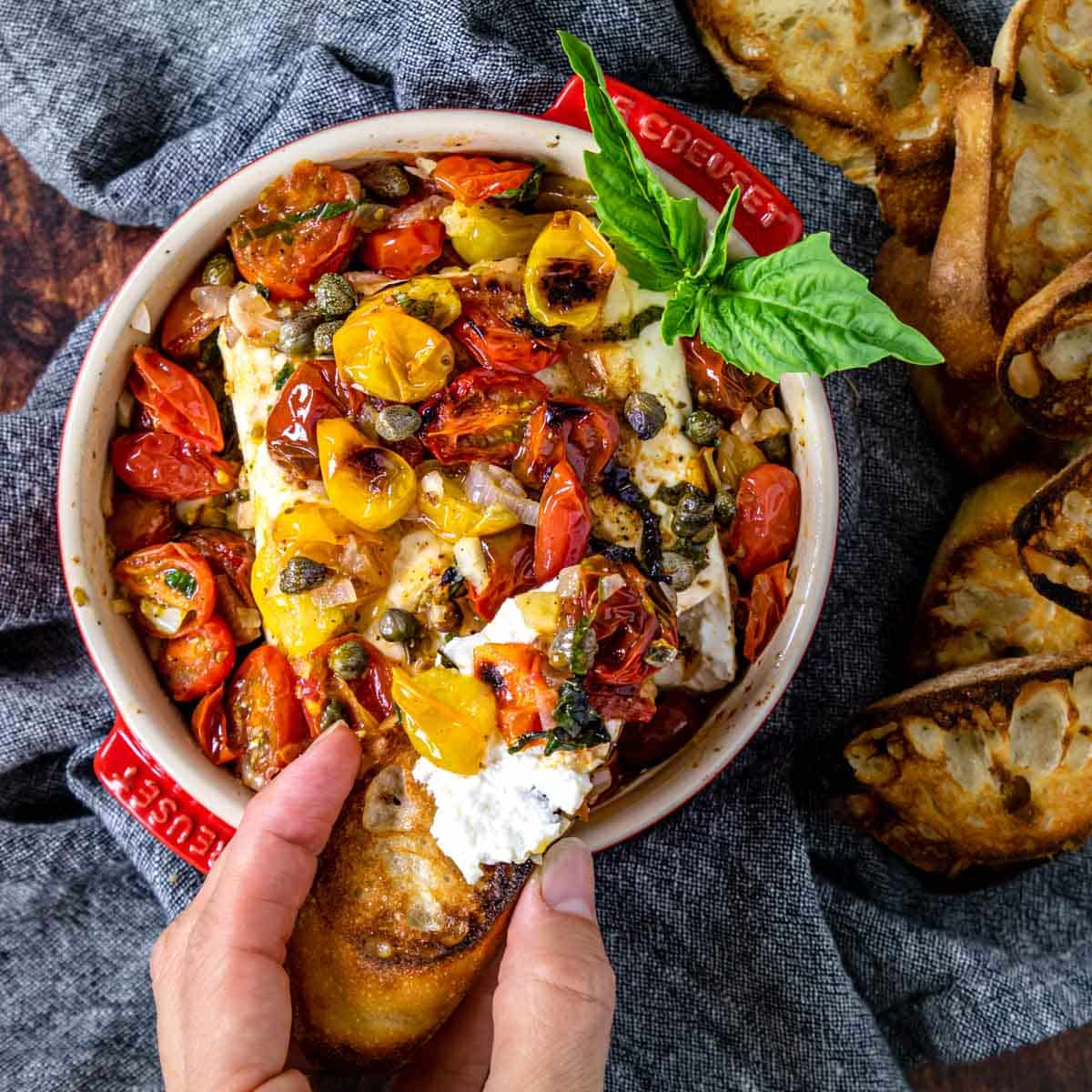 baked feta appetizer in a dish being scooped with crostini