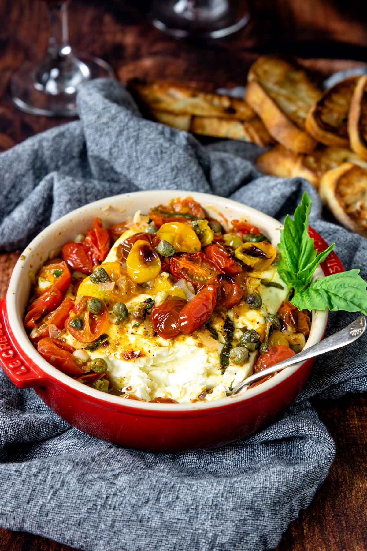 baked feta topped with tomatoes in a red baking dish