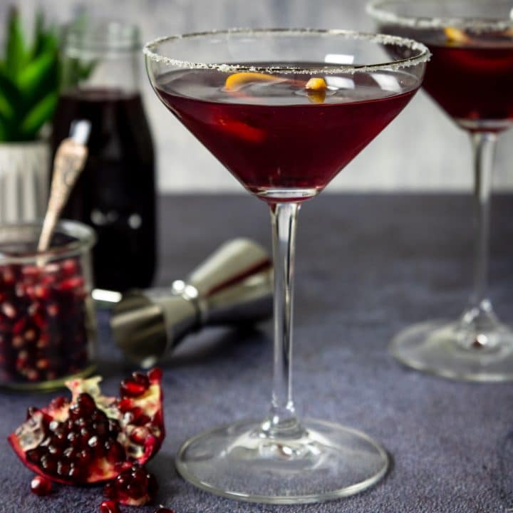 pomegranate martini in a stemmed glass with and orange twist
