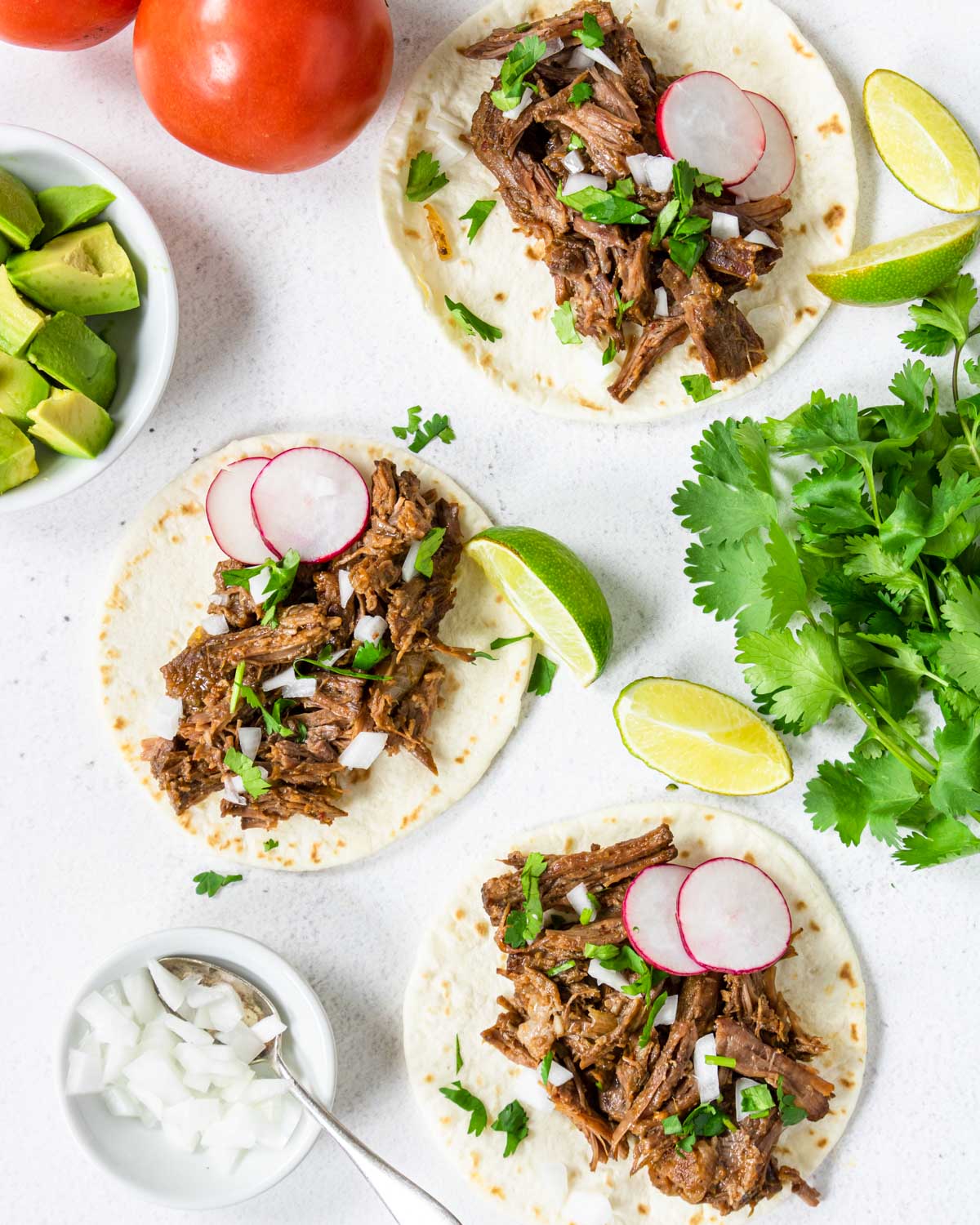 Barbacoa tacos topped with white onions and cilantro