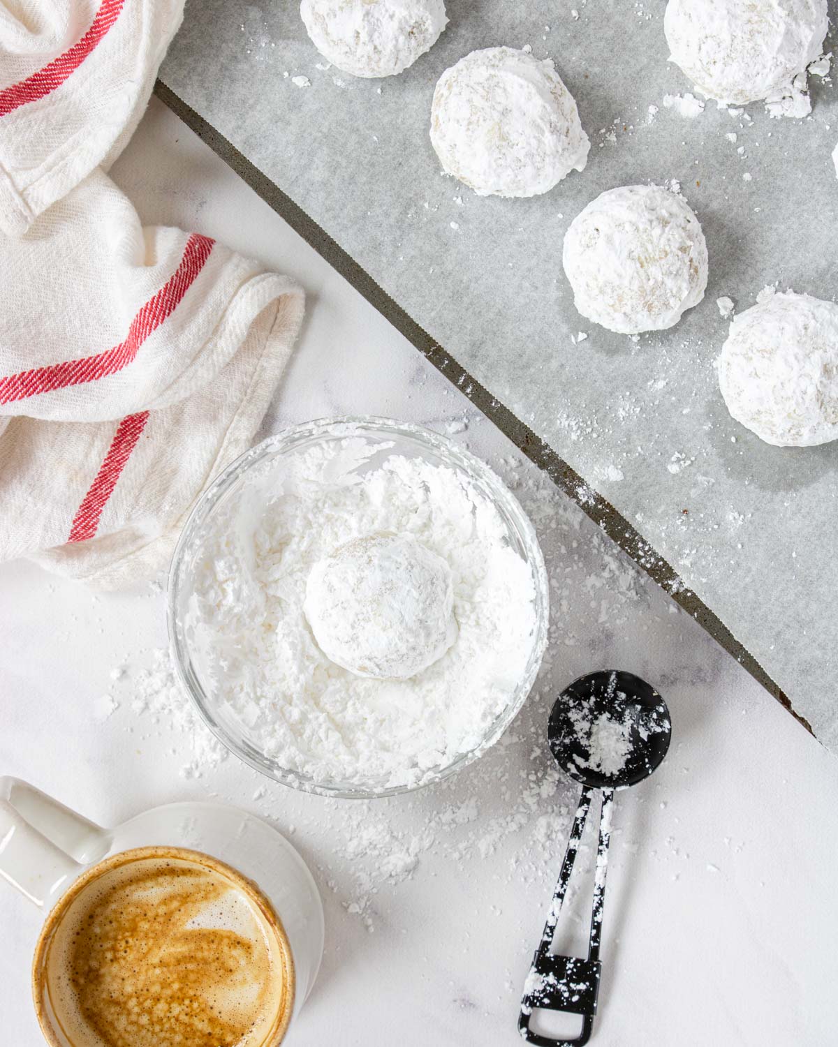 dipping pecan snowball cookies in powdered sugar for a second time