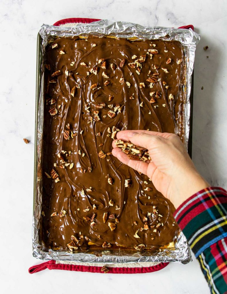 sprinkling pecans on top of saltine toffee