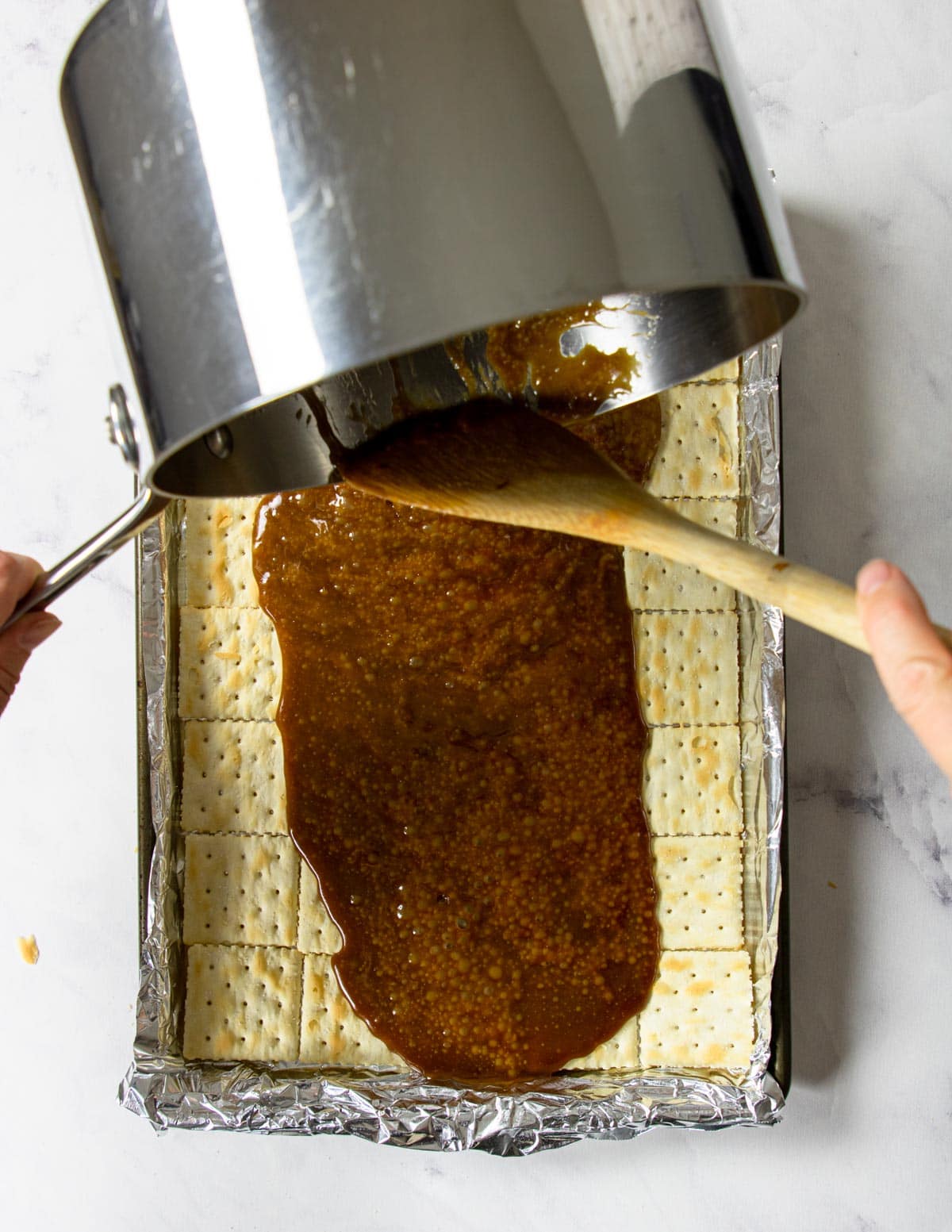 pouring homemade caramel over crackers