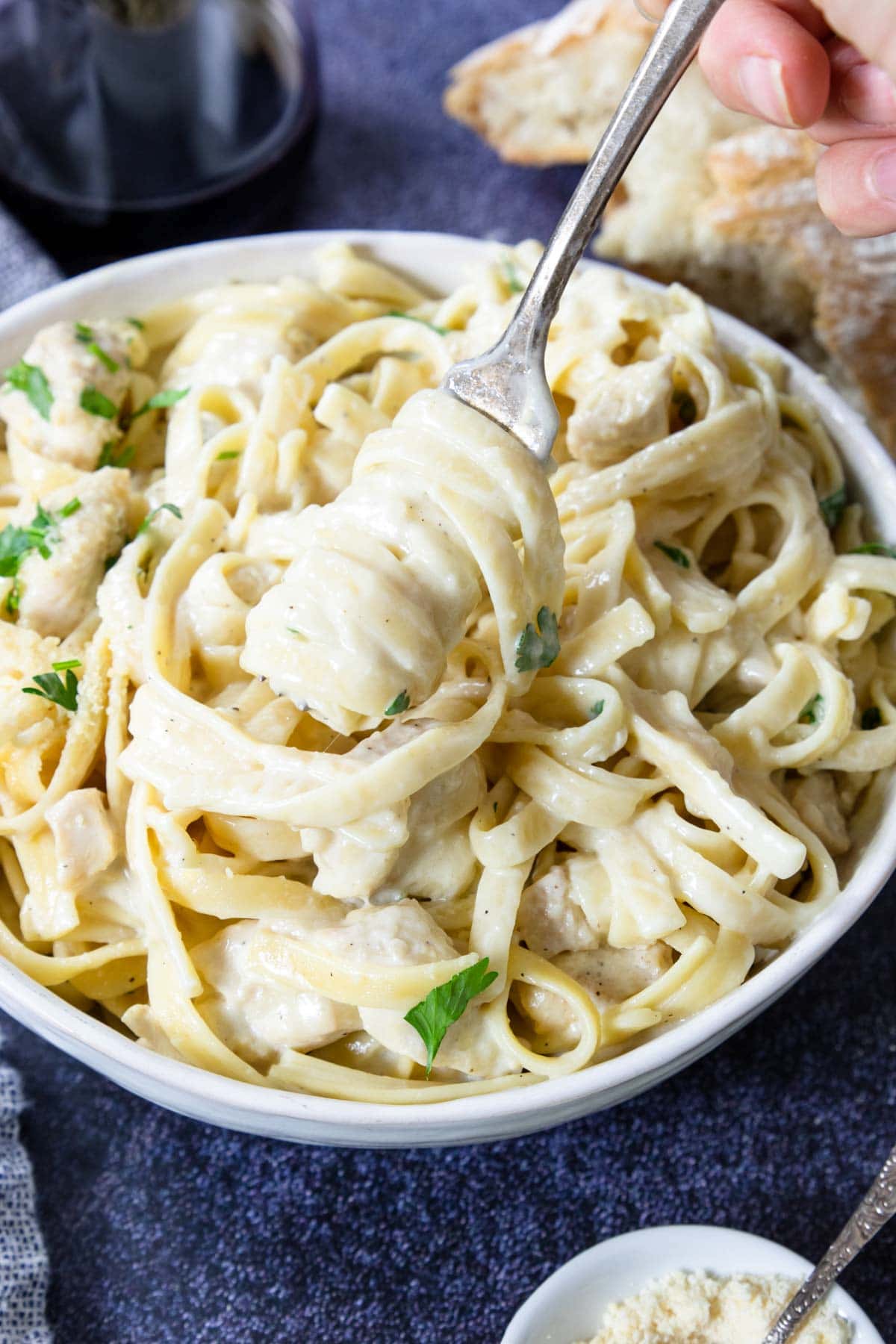 a bowl of really creamy chicken alfredo pasta with a fork twirling the pasta