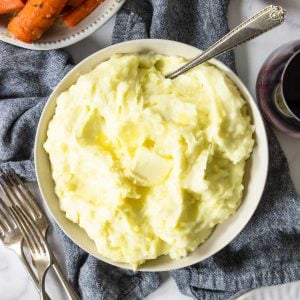 yukon gold mashed potatoes topped with a pat of butter and roasted carrots to the side