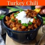 turkey chili in a bowl topped with green onions and sour cream with Pinterest text