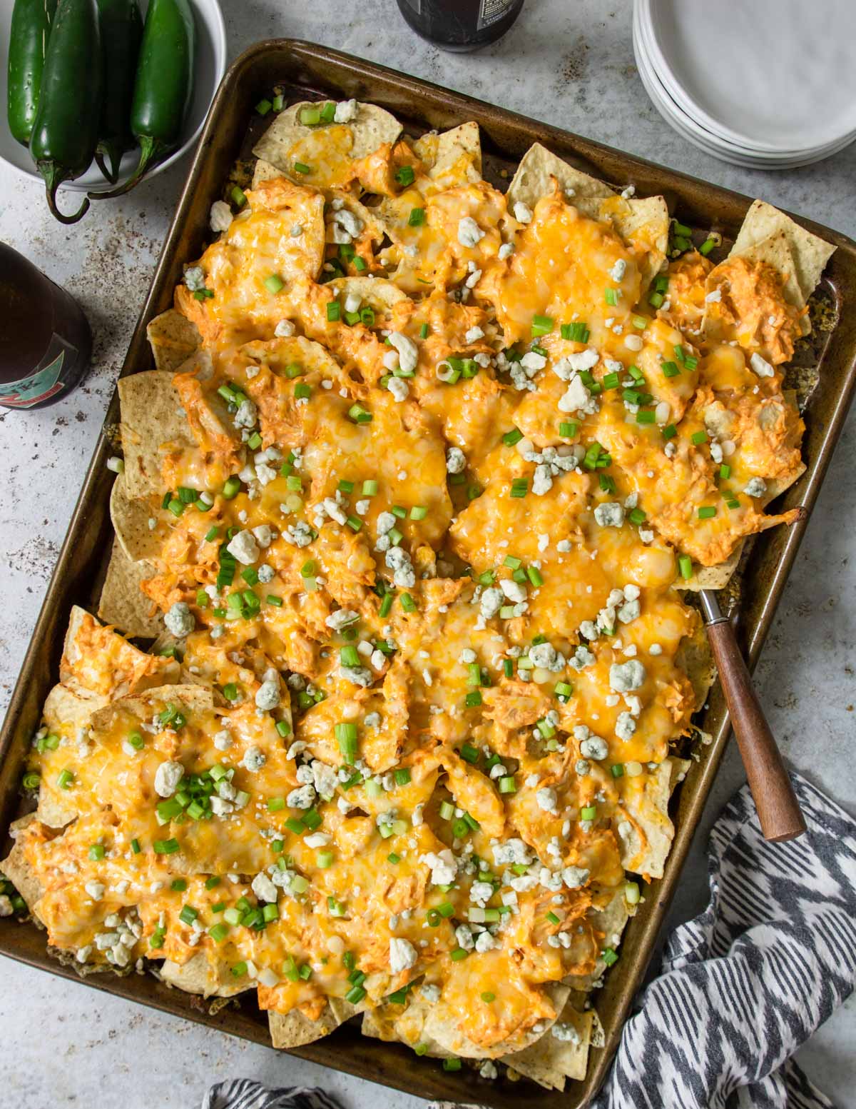 a tray of buffalo chicken nachos topped with green onions 