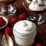 whipped cream in a mason jar with chocolate pudding in the background