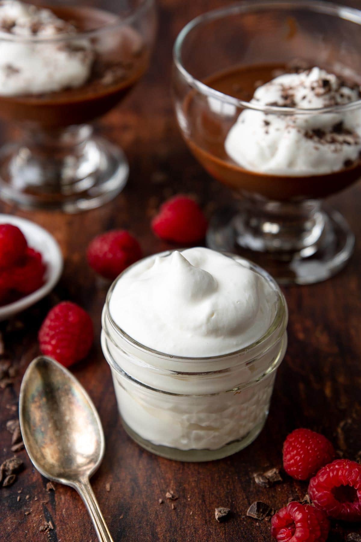whipped cream in a mason jar with chocolate pudding in the background