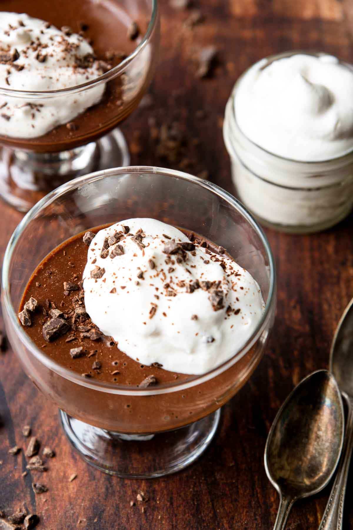a bowl of chocolate pudding topped with whipped cream and chopped chocolate