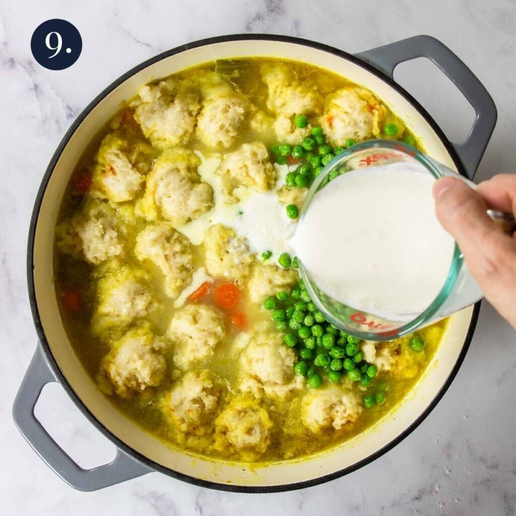 pouring cream and peas into chicken stew with dumplings
