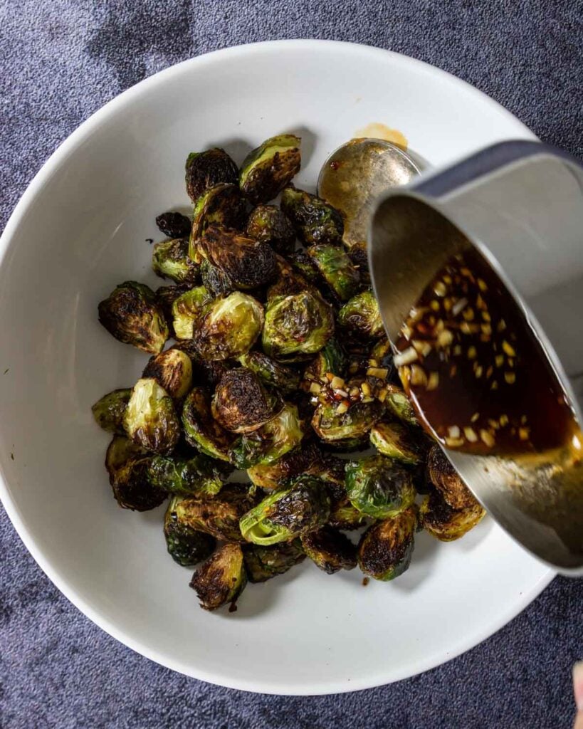 pouring ginger soy glaze over the brussels