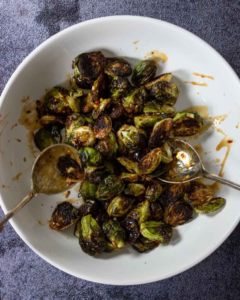 tossing roasted brussels in an Asian sauce