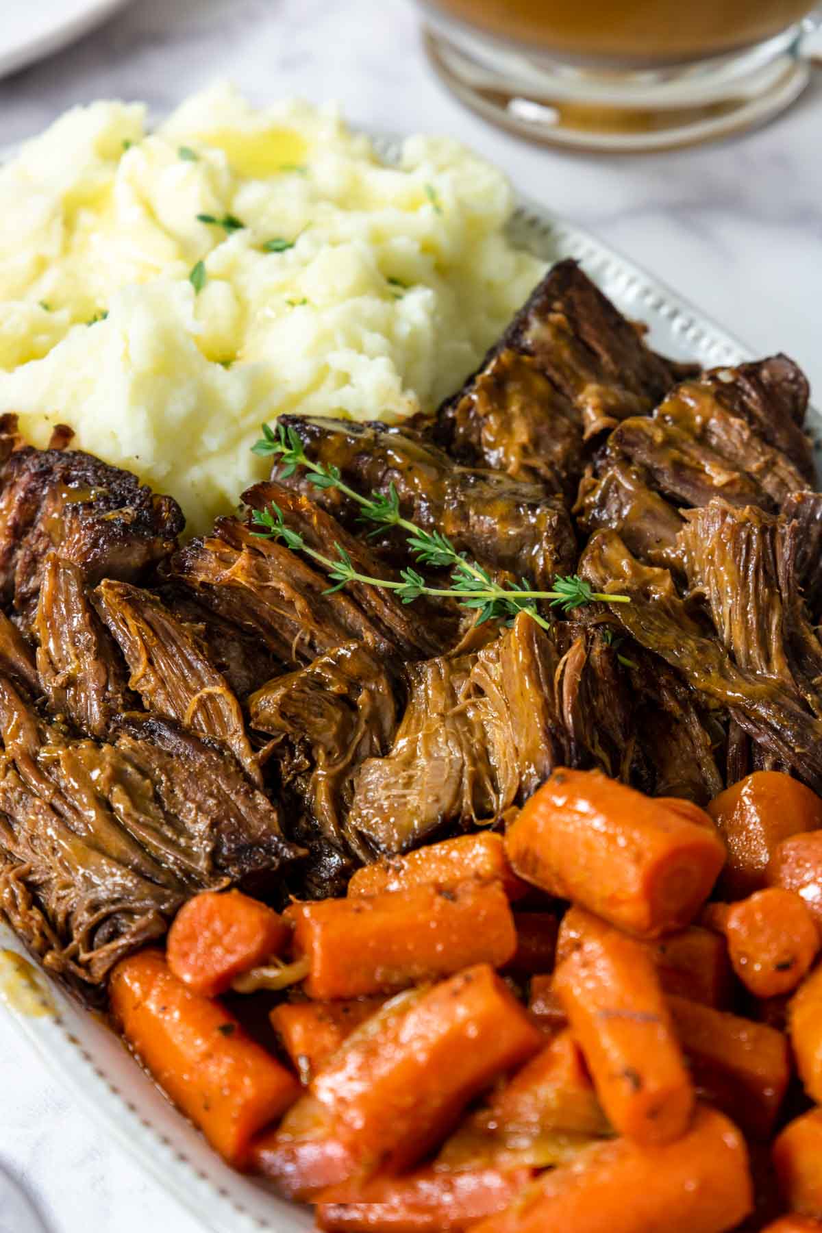 a serving plate with pot roast, mashed potatoes, and cooked carrots