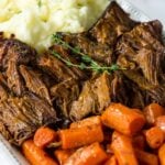 a close up of pot roast,cooked carrots and mashed potatoes