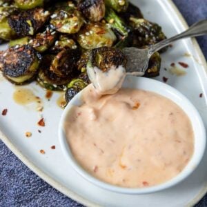 a bowl of sambal aioli with a brussel sprout dipping in