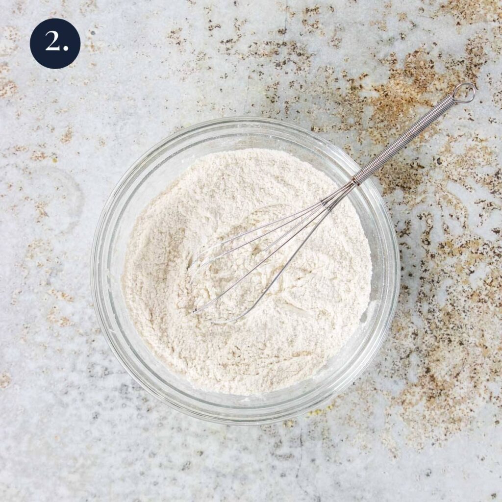 a bowl of flour with a whisk