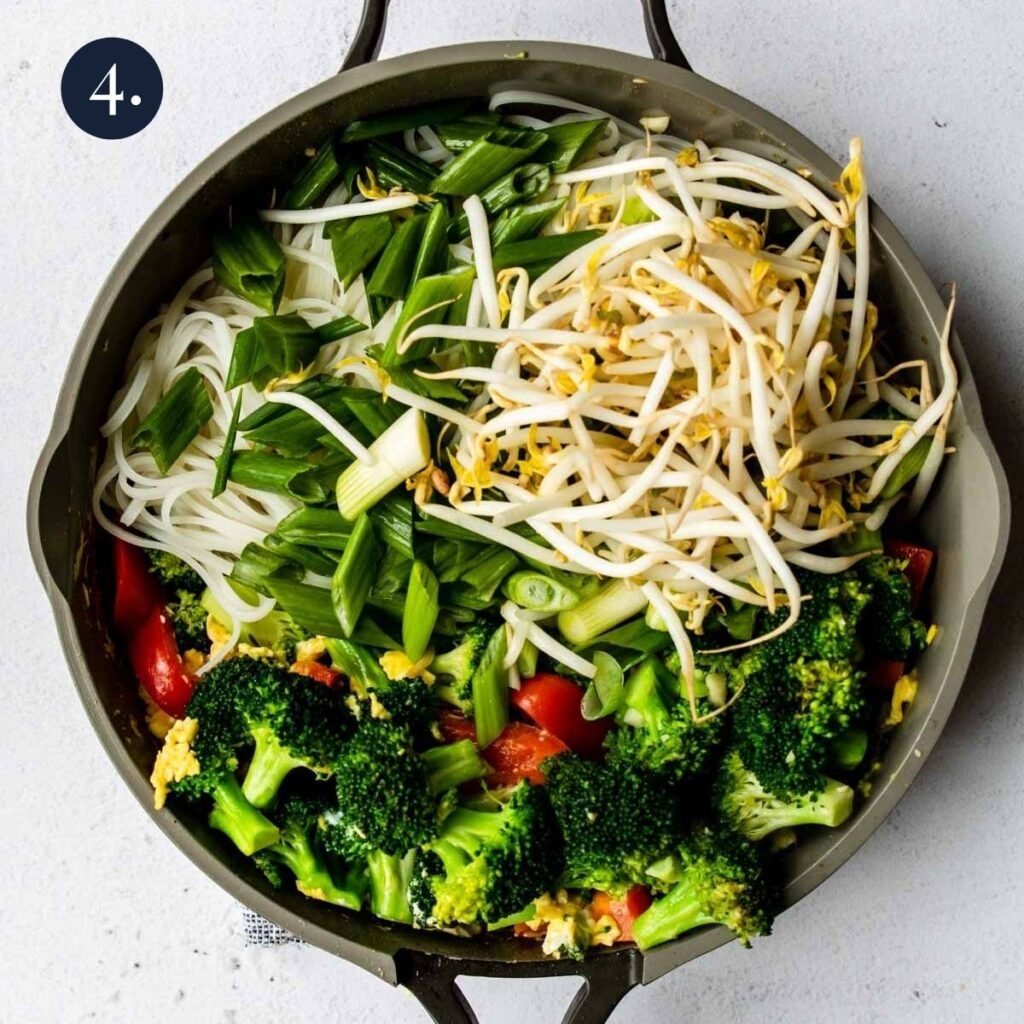a skillet full of veggies and rice noodles