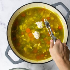 dumplings being dropped into chicken soup