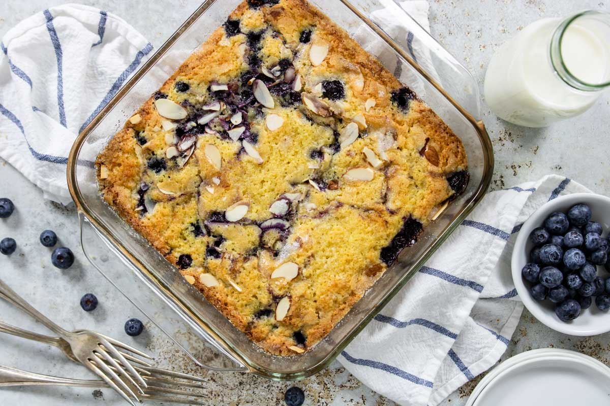 a lemon blueberry coffee cake on a table with milk and blueberries
