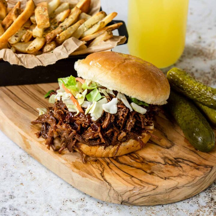 BBQ Beef sandwich on a cutting board with fries