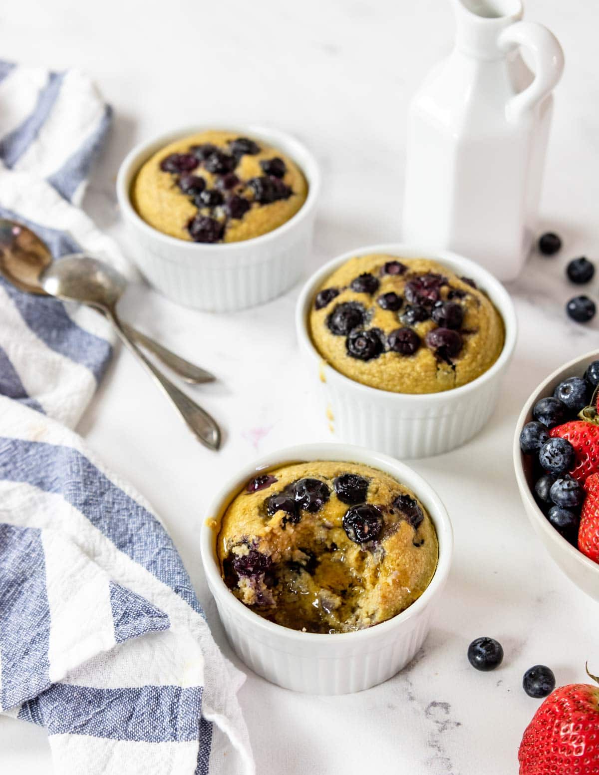baked steel cut oats with blueberries drizzled with syrup, fresh fruit to the side