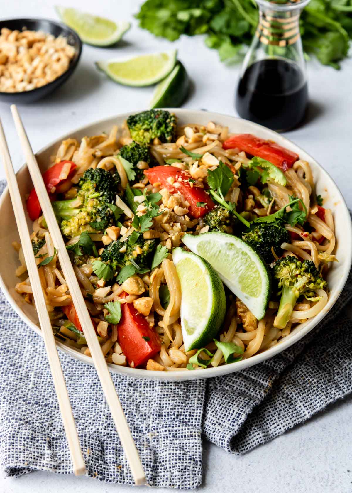 Vegetable Pad Thai in a white bowl with limes and chop sticks